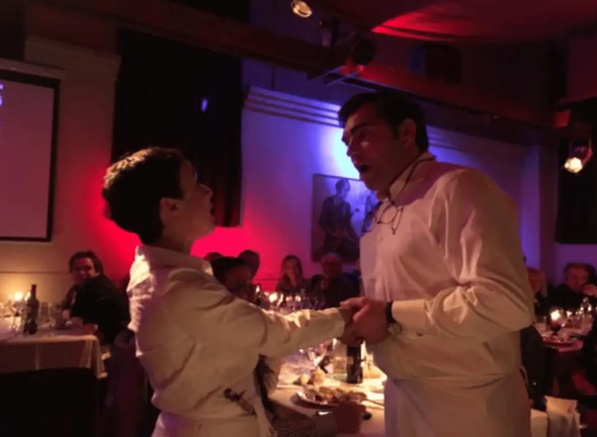 Dos cantantes de La Castafiore interpretando un dúo de ópera entre las mesas